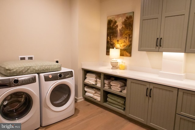 washroom featuring independent washer and dryer, cabinets, and light wood-type flooring