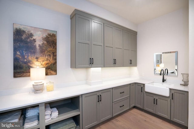 clothes washing area with sink and light wood-type flooring