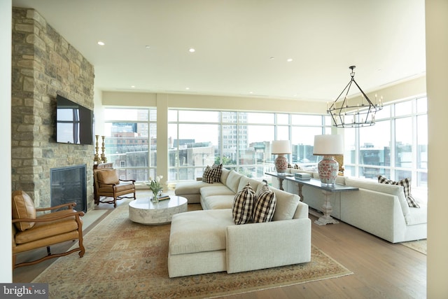 living room featuring a fireplace, a chandelier, plenty of natural light, and light wood-type flooring