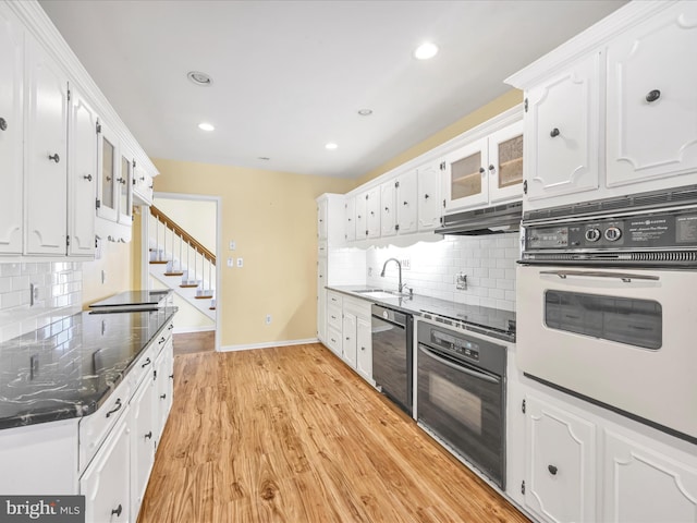 kitchen featuring black dishwasher, oven, and white cabinets