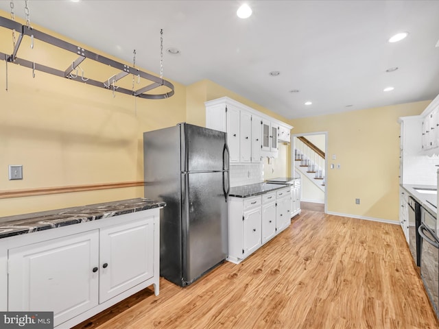 kitchen with black fridge, white cabinetry, light hardwood / wood-style floors, and tasteful backsplash