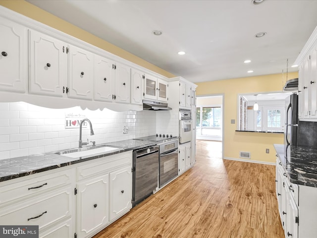 kitchen with white cabinetry, sink, decorative backsplash, black appliances, and light wood-type flooring