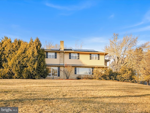 view of front of property with a front lawn and solar panels