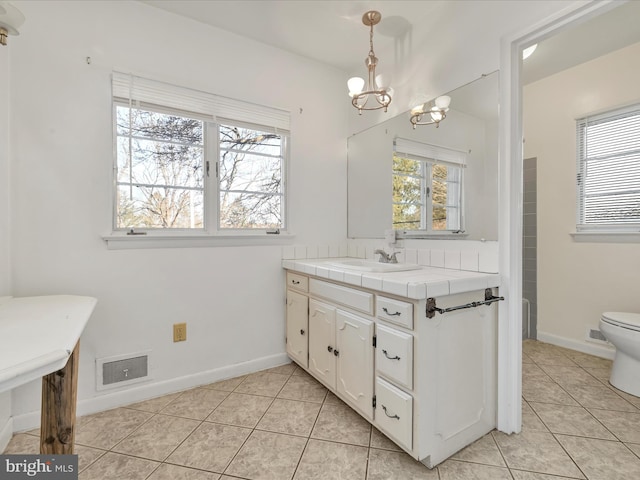 bathroom with tile patterned flooring, vanity, toilet, and a chandelier