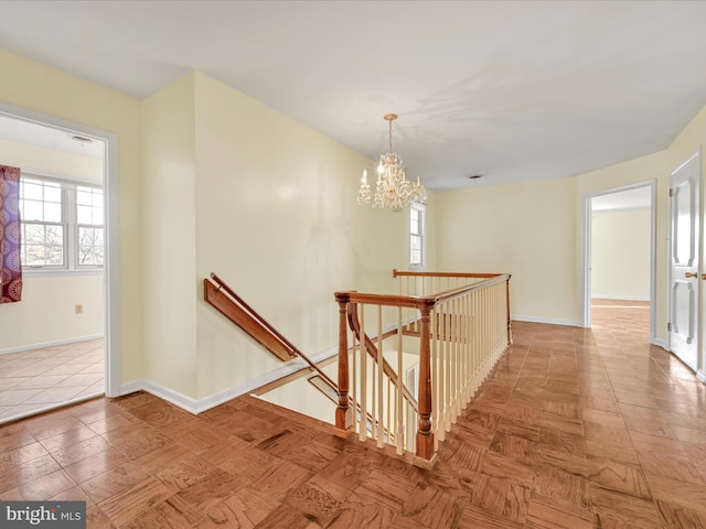 hall with an inviting chandelier, parquet floors, and a healthy amount of sunlight