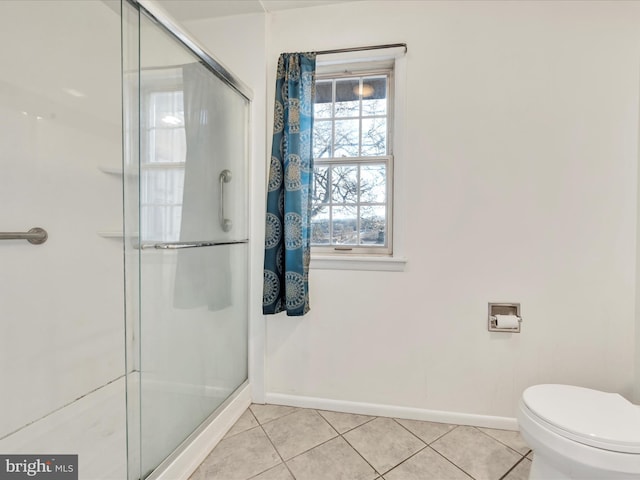 bathroom featuring tile patterned flooring, a shower with door, and toilet