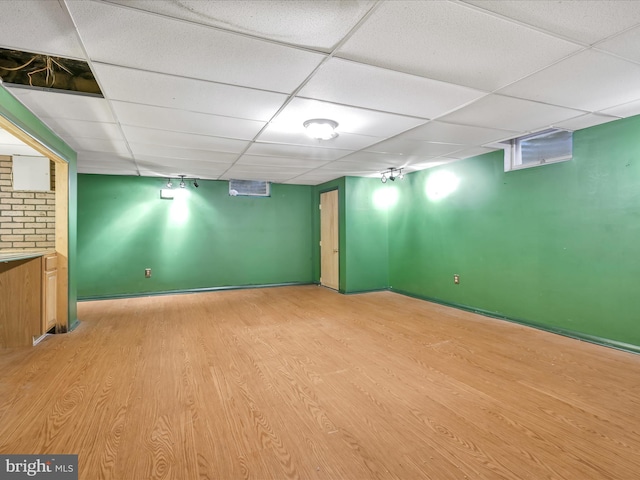 basement with a paneled ceiling and light wood-type flooring