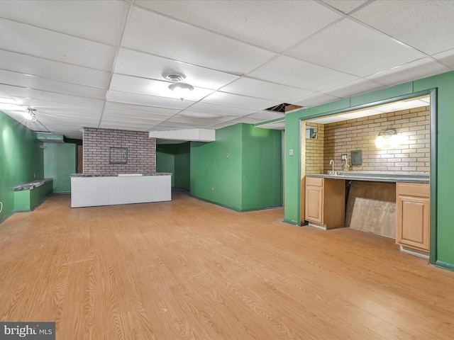 basement with a drop ceiling and light hardwood / wood-style floors