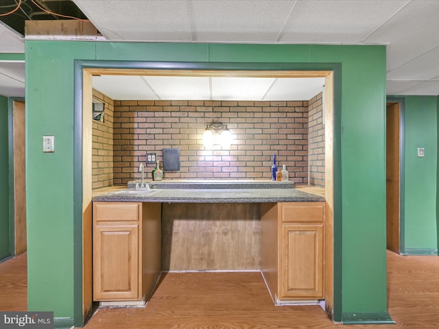 bar with wood-type flooring, brick wall, sink, and a paneled ceiling