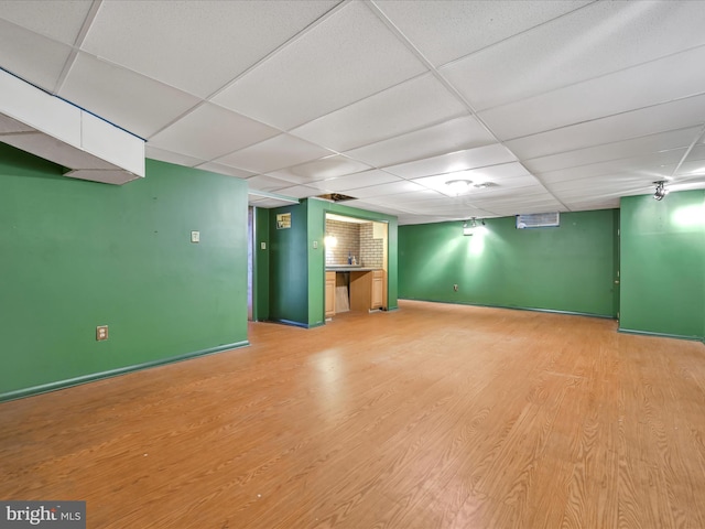 basement featuring a paneled ceiling and light wood-type flooring