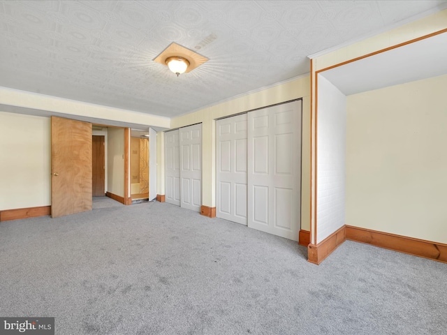 unfurnished bedroom with light carpet, a textured ceiling, and multiple closets