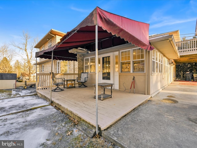 snow covered rear of property with a deck