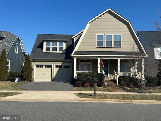 view of front of house featuring roof with shingles, covered porch, a gambrel roof, a garage, and driveway