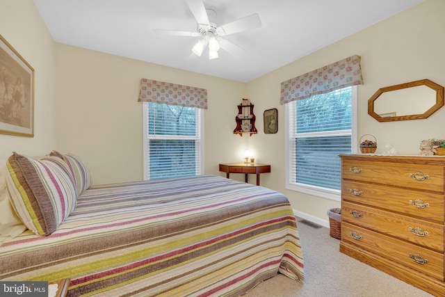 bedroom with ceiling fan, light colored carpet, and multiple windows