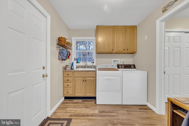 clothes washing area with cabinets, washer and dryer, sink, and light wood-type flooring