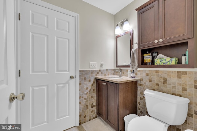 bathroom featuring vanity, tile walls, and toilet