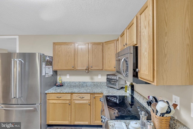 kitchen with light stone counters, stainless steel appliances, a textured ceiling, and light brown cabinets