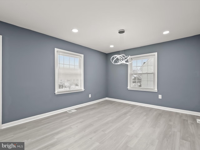 unfurnished dining area with a notable chandelier and light wood-type flooring