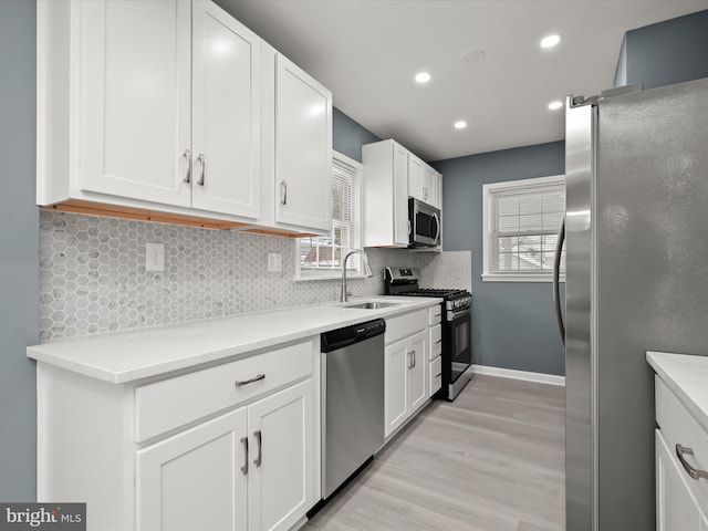 kitchen featuring stainless steel appliances, sink, decorative backsplash, and white cabinets