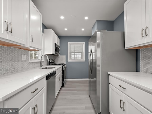 kitchen with sink, light stone counters, tasteful backsplash, stainless steel appliances, and white cabinets