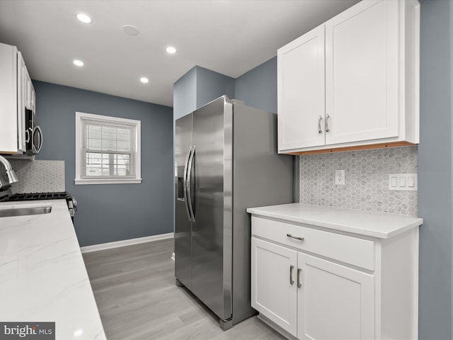 kitchen featuring white cabinetry, appliances with stainless steel finishes, light stone counters, and backsplash