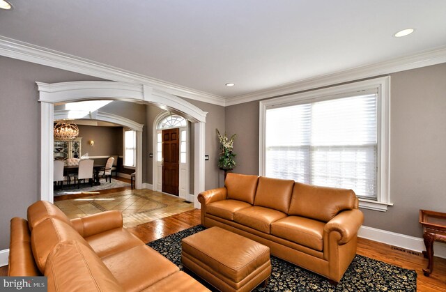 living room with hardwood / wood-style flooring, crown molding, and an inviting chandelier