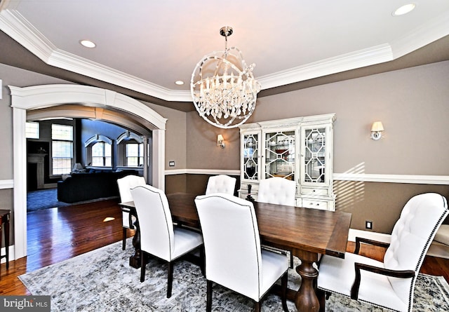 dining room featuring dark wood-type flooring, a tray ceiling, crown molding, and a notable chandelier