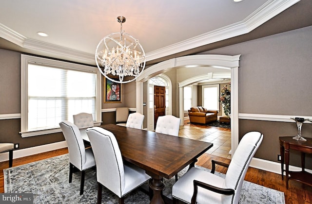 dining area featuring ornamental molding, wood-type flooring, and a notable chandelier