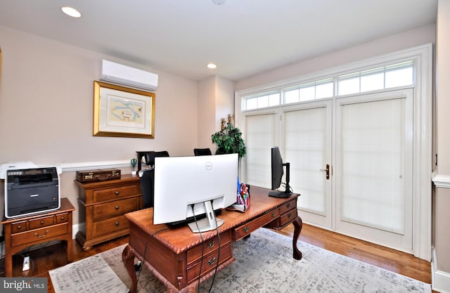 office area with a wall mounted air conditioner and light hardwood / wood-style flooring