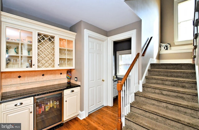 bar featuring backsplash, wine cooler, and dark hardwood / wood-style flooring