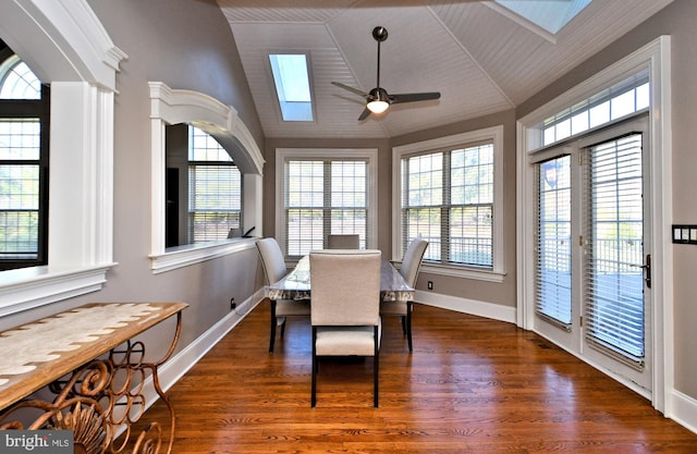 dining space featuring dark hardwood / wood-style flooring, ceiling fan, and vaulted ceiling with skylight