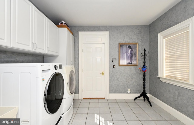 laundry area with cabinets, light tile patterned floors, and washer and clothes dryer