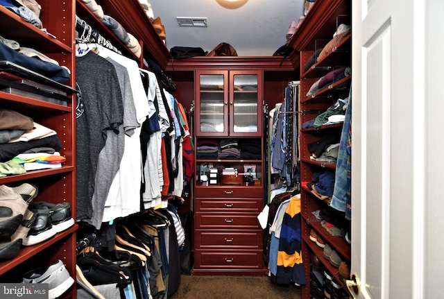 walk in closet with dark colored carpet