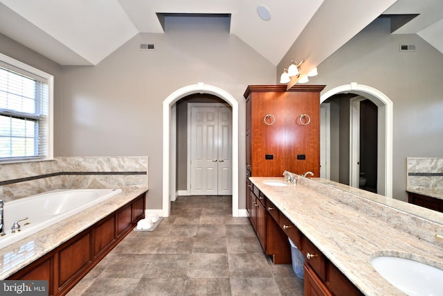 bathroom with vanity, lofted ceiling, and a washtub