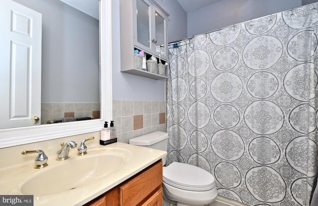 bathroom featuring vanity, toilet, and tile walls