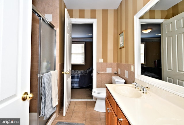 bathroom featuring tile patterned flooring, tile walls, vanity, an enclosed shower, and toilet