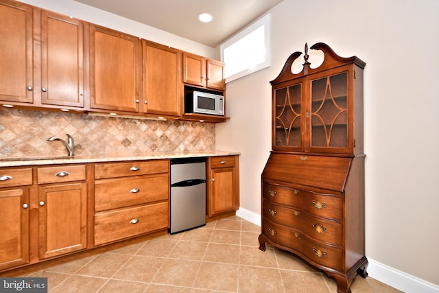 kitchen with sink, refrigerator, light tile patterned floors, white microwave, and backsplash