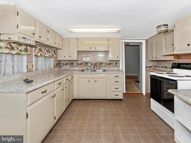 kitchen with sink, light stone countertops, cream cabinets, and electric range oven