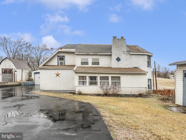 back of property with a garage, an outdoor structure, and a yard