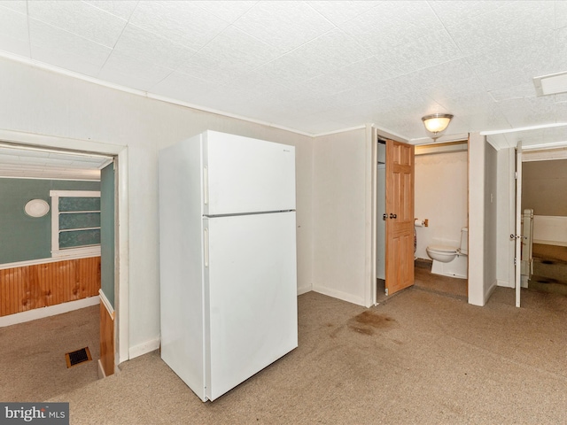 interior space with connected bathroom, wooden walls, and white refrigerator