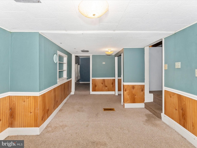 carpeted spare room with built in shelves and wooden walls