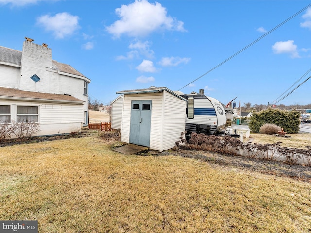 back of house with a yard and a storage unit