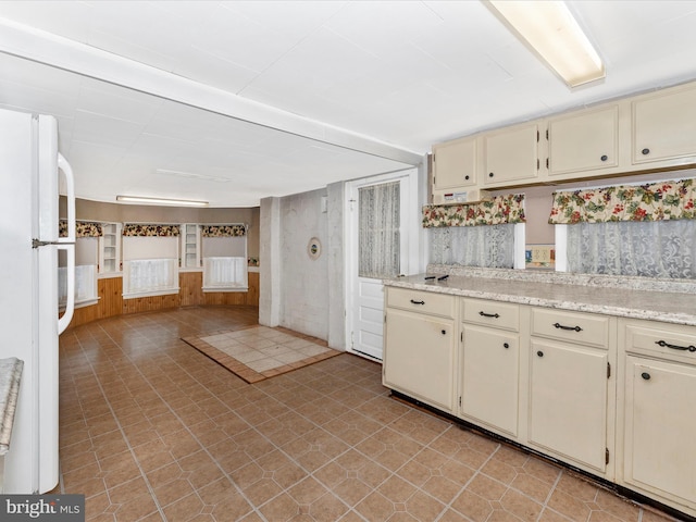 kitchen with white refrigerator, cream cabinets, and light stone counters