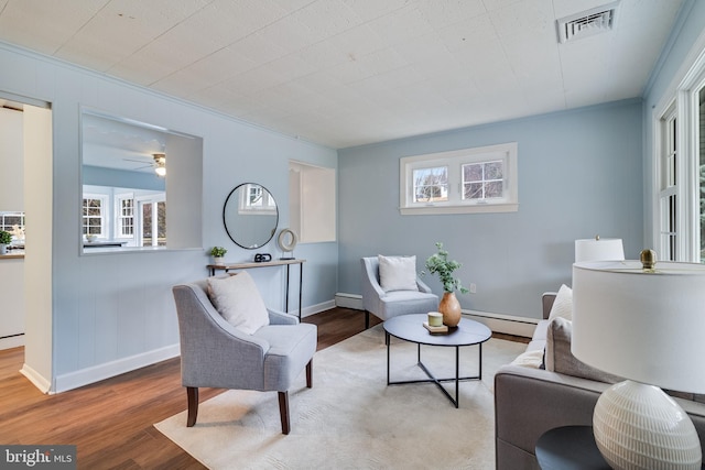 living room featuring baseboard heating, plenty of natural light, and hardwood / wood-style flooring