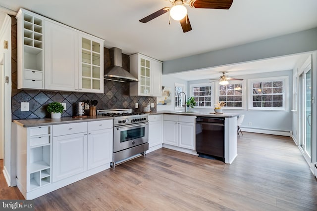 kitchen with wall chimney range hood, high end range, black dishwasher, white cabinets, and kitchen peninsula