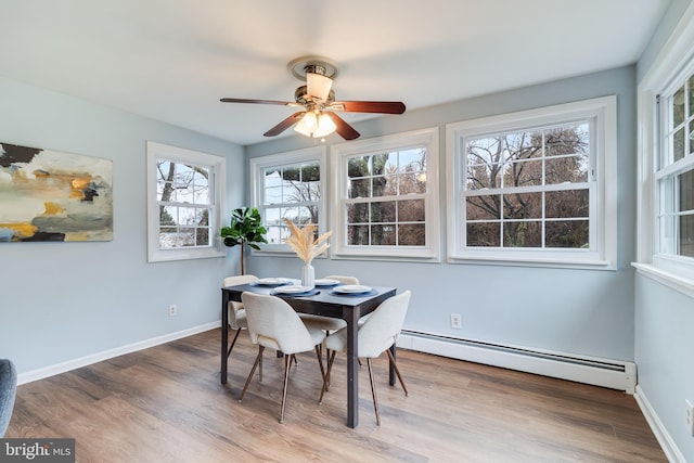 dining space with hardwood / wood-style flooring, a baseboard radiator, and ceiling fan