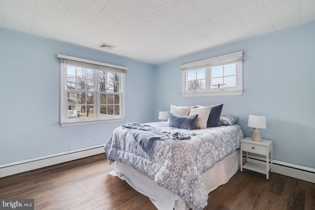 bedroom with dark hardwood / wood-style flooring and a baseboard heating unit