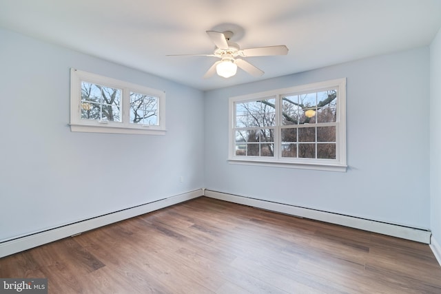 empty room featuring wood-type flooring, plenty of natural light, a baseboard heating unit, and ceiling fan