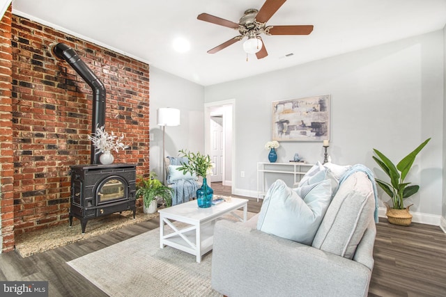 living room featuring dark hardwood / wood-style floors, ceiling fan, and a wood stove