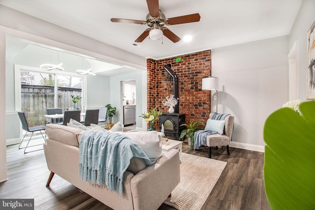 living room featuring dark wood-type flooring, ceiling fan, and a wood stove